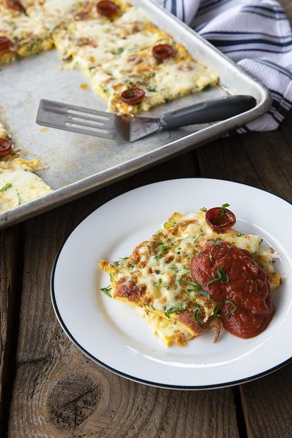 Pizza Frittata: delicious slices baked egg with spicy pepperoni, flavourful green onions and fresh parsley, and melted mozzarella cheese throughout. We don't stop there, though! We also top it with more grated mozzarella and pepperoni and give it a quick run under the broiler to melt the cheese and crisp up the pepperoni, then serve it with marinara or pizza sauce.