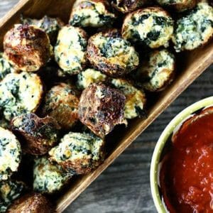 Cheesy Spinach Puffs in wooden serving dish, wooden bench, anthropologie nesting measuring cup with marinara sauce