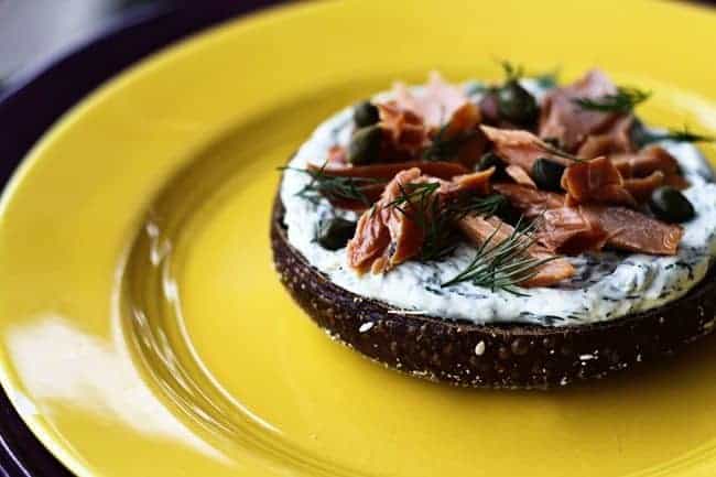 Lemon Dill Spreadable Cream Cheese on a black Russian bagel with smoked salmon and capers from Foodie with Family.