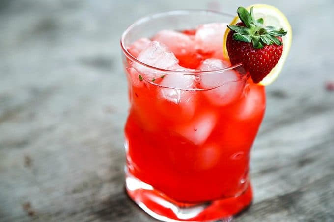 boozy strawberry basil lemonade, bormioli rocco sorgente highball glass, strawberry and lemon garnish, rustic wood table
