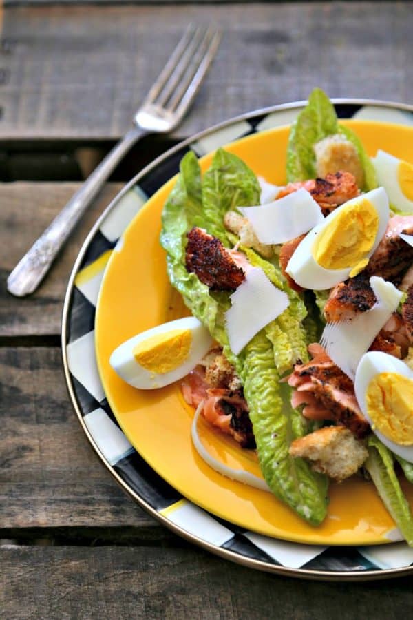 Simple, fresh, and filling main dish salad for spring! Blackened Salmon Caesar Salad with torn croutons, hard boiled egg, homemade dressing, and flaked blackened salmon gives the traditional Caesar salad a flavourful facelift!