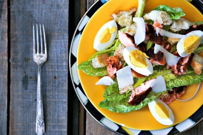 Simple, fresh, and filling main dish salad for spring! Blackened Salmon Caesar Salad with torn croutons, hard boiled egg, homemade dressing, and flaked blackened salmon gives the traditional Caesar salad a flavourful facelift!