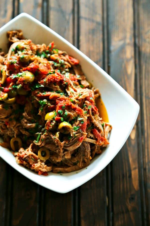 Slow Cooker Italian Shredded Beef full of sun dried tomatoes, wine, garlic, fire roasted tomatoes, olives, and capers from foodiewithfamily.com