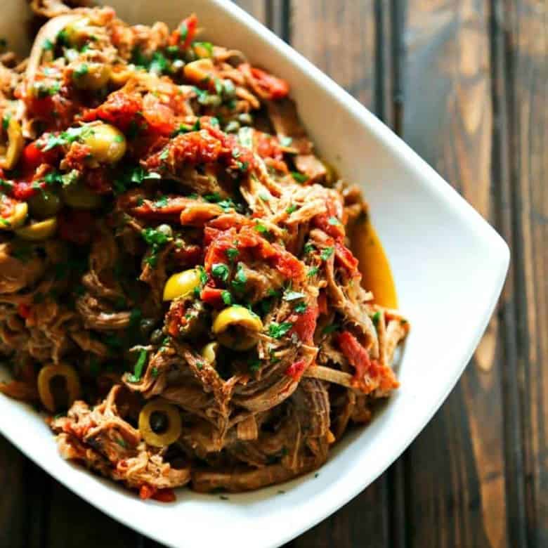 Slow Cooker Italian Shredded Beef full of sun dried tomatoes, wine, garlic, fire roasted tomatoes, olives, and capers from foodiewithfamily.com