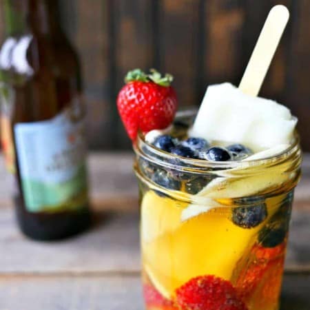 Hard Cider Sangria-by-the-Glass is fresh fruits soaked in crisp hard cider with a lime ice pop stir stick.