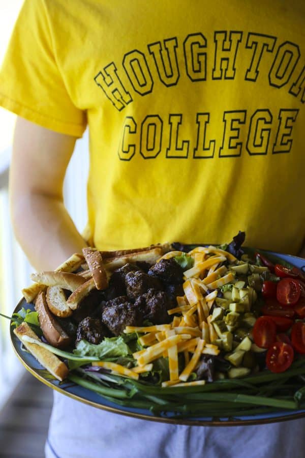 Cheeseburger Salad from foodiewithfamily.com with sesame bun croutons. grilled meatballs and green onions, cheese, pickles, tomatoes, and hot fries.