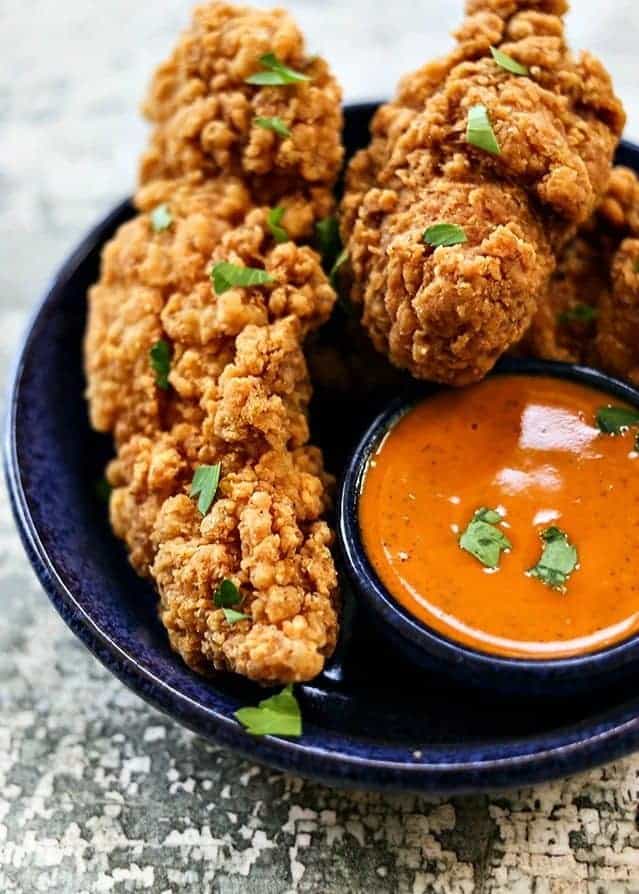 Garlic Buffalo Sauce with chicken tenders in a blue plate.