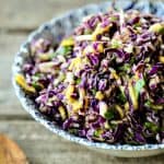 Spicy Mango Slaw is crunchy purple cabbage with a hint of tropical sweetness from just barely ripe mango, and the tart and tangy lime juice and honey dressing gets a flavour boost from minced red onion and fragrant cilantro.