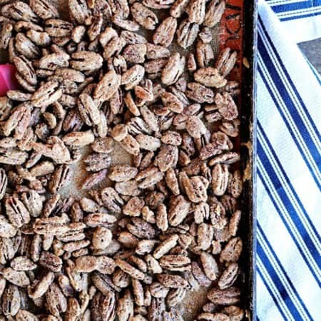 Candied Maple Pecans on a silpat lined antique metal sheet pan, crisp blue and white cotton towel, wooden bench