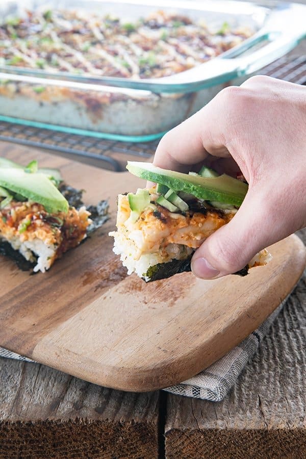 sushi bake on nori with cucumbers and avocado being lifted