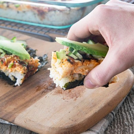 sushi bake on nori with cucumbers and avocado being lifted