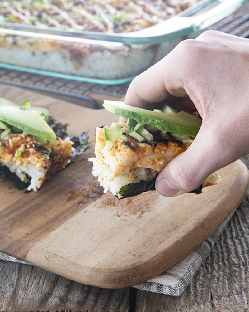 sushi bake on nori with cucumbers and avocado being lifted
