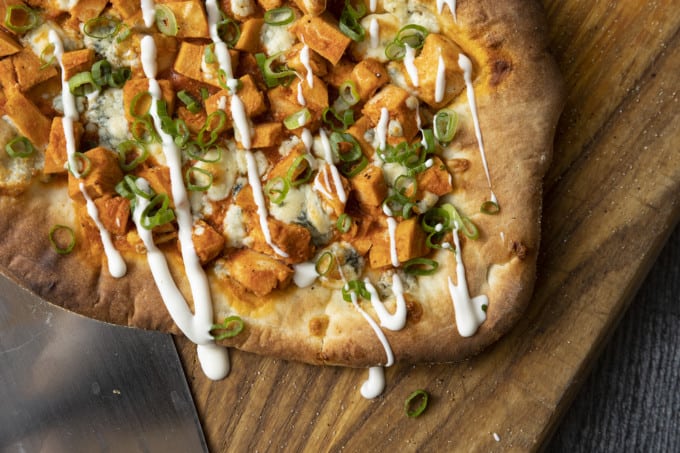 Tender cubes of Spicy Buffalo chicken, blue cheese crumbles or another cheese of your choice, thinly sliced green onions, and a drizzle of blue cheese dressing or ranch dressing top flatbread proving that great food doesn't have to be complicated! Buffalo Chicken Flatbread is equally fabulous as a great appetizer for game day or as an easy dinner.