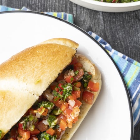 Choripan: Garlicky, spicy, smoky chorizo sausage is slowly grilled to perfection before being split, seared over high heat, and served on a bun with fresh chimichurri sauce and salsa a la criolla; the messier the better!