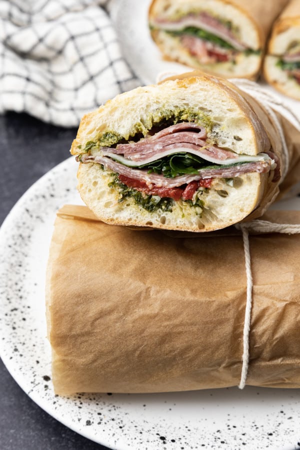 This is no ordinary Salami Sandwich; a crusty baguette is stuffed to bursting with a variety of salamis, roasted red pepper, pesto sauce, provolone cheese, fresh basil, and dressed arugula, then tightly wrapped and stashed in the refrigerator overnight. Then you can slice it all up and arrange it on a platter for a party or stretch it out for up to 5 days! And let me tell you, if you slice a little off of this every day for lunch with a cup of soup or bag of chips, you're going to feel very clever indeed. If you're feeling generous, pop it in a lunch bag for a school lunch that will make your kid the envy of the school.