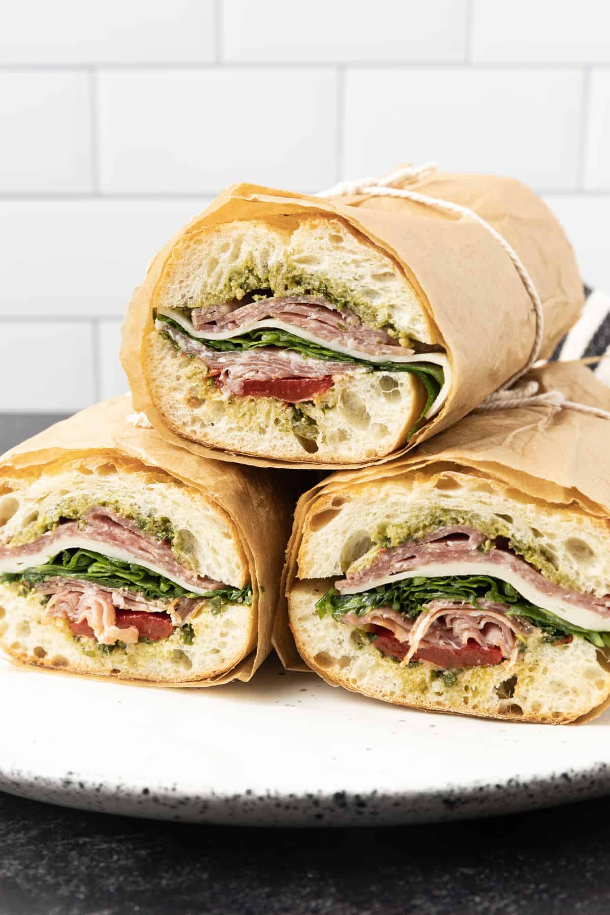 This is no ordinary Salami Sandwich; a crusty baguette is stuffed to bursting with a variety of salamis, roasted red pepper, pesto sauce, provolone cheese, fresh basil, and dressed arugula, then tightly wrapped and stashed in the refrigerator overnight. Then you can slice it all up and arrange it on a platter for a party or stretch it out for up to 5 days! And let me tell you, if you slice a little off of this every day for lunch with a cup of soup or bag of chips, you're going to feel very clever indeed. If you're feeling generous, pop it in a lunch bag for a school lunch that will make your kid the envy of the school.