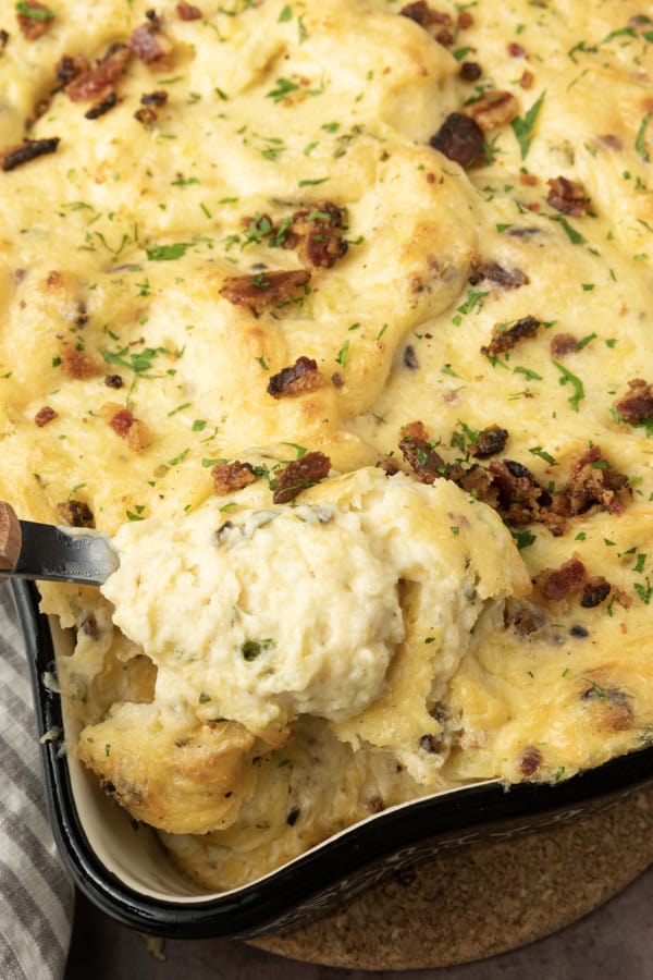 Get ready to dig into a baking dish filled with piping hot, irresistibly golden crusted, super creamy Twice Baked Mashed Potatoes. This make-ahead perfect side dish combines everything you love about creamy mashed potatoes, baked and twice baked potatoes; grated cheese, sour cream, crispy bacon, fresh herbs, and a whisper thin crispy crust at the edges. The only thing better than the taste of Twice Baked Mashed Potatoes casserole is its convenience. You can make it up to three days ahead of time and reheat before serving or you can make it, wrap it tightly, and freeze it for up to a month.