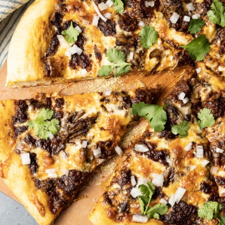 Birria Pizza: Chewy crust topped with tender shredded birria beef, smoky birria stew, loads of melted cheese, chopped sweet onion, fresh cilantro, a squeeze of fresh lime, and a bowl of red chile sauce for dipping. Imagine the best tacos you’ve ever tasted turned into a pizza and you have an idea just how fabulous this pizza is.