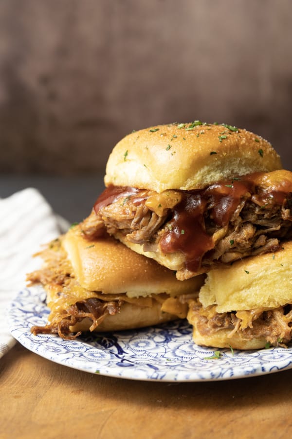 Easy Pulled Pork Sliders: Pillowy rolls filled with delicious, mouth-watering, tender pulled pork, bbq sauce, and cheese are brushed with melted butter, garlic, and herbs, then baked to toasty, melty perfection. They’re like the little black dress of the sandwich world and perfect for every occasion. Bonus: They're done in 30 minutes from start to finish!