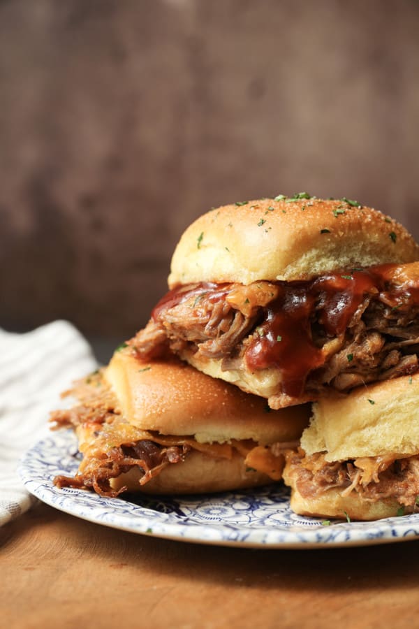 Easy Pulled Pork Sliders: Pillowy rolls filled with delicious, mouth-watering, tender pulled pork, bbq sauce, and cheese are brushed with melted butter, garlic, and herbs, then baked to toasty, melty perfection. They’re like the little black dress of the sandwich world and perfect for every occasion. Bonus: They're done in 30 minutes from start to finish!