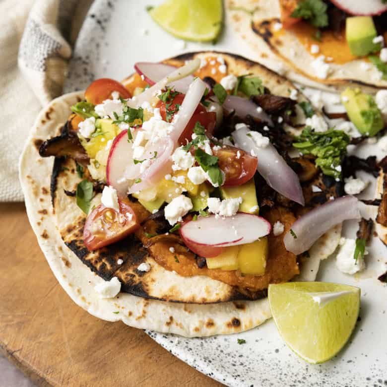 This crispy mushroom taco recipe with the works is for all my obsessive mushroom loving friends. It’s unapologetically mushroom forward, so this is not for you if you’re not into fungi. It’s almost laughably easy to make this substantial meatless taco recipe. Roasting the seasoned mushrooms on a metal sheet pan in a hot oven gives them delectable crispy edges.