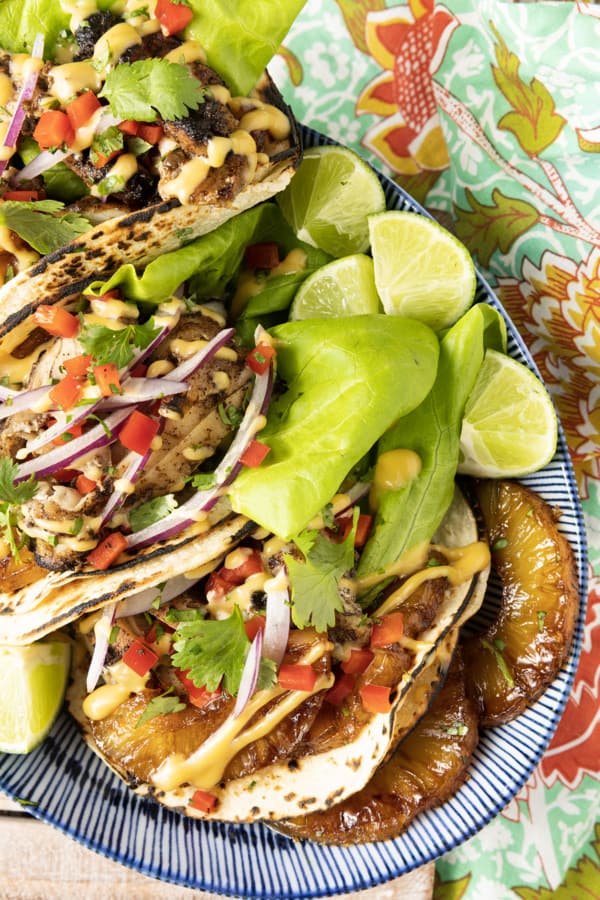 Make taco nights magical with jerk chicken tacos! Fresh lettuce leaves stacked on charred tortillas are piled high with juicy jerk chicken, grilled pineapple slices, diced bell peppers, thinly sliced onions, a drizzle of sauce or spoonful of mango salsa.