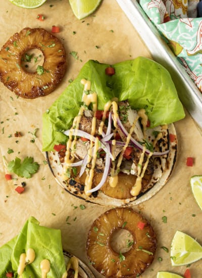 Make taco nights magical with jerk chicken tacos! Fresh lettuce leaves stacked on charred tortillas are piled high with juicy jerk chicken, grilled pineapple slices, diced bell peppers, thinly sliced onions, a drizzle of sauce or spoonful of mango salsa.