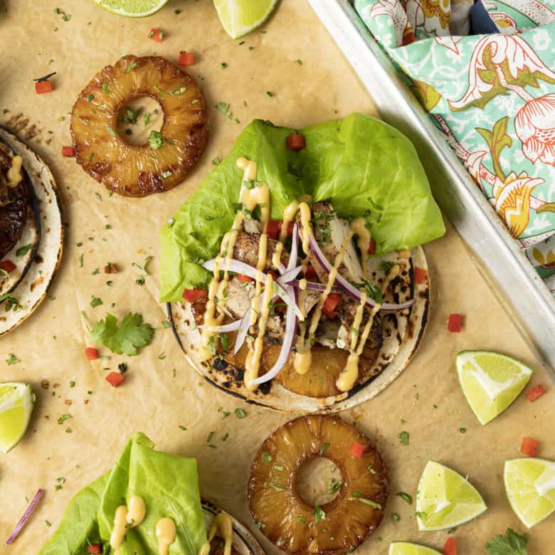 Make taco nights magical with jerk chicken tacos! Fresh lettuce leaves stacked on charred tortillas are piled high with juicy jerk chicken, grilled pineapple slices, diced bell peppers, thinly sliced onions, a drizzle of sauce or spoonful of mango salsa.