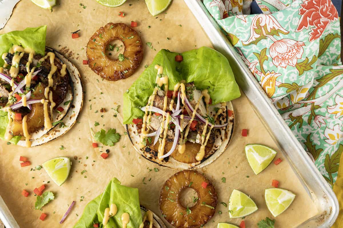 Make taco nights magical with jerk chicken tacos! Fresh lettuce leaves stacked on charred tortillas are piled high with juicy jerk chicken, grilled pineapple slices, diced bell peppers, thinly sliced onions, a drizzle of sauce or spoonful of mango salsa.