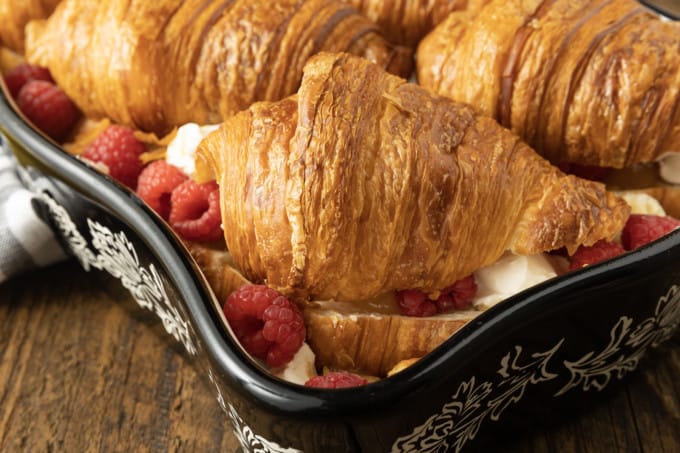 Rich, buttery, & indulgent, this creamy lemon and raspberry croissant bread pudding recipe is almost unbelievably easy to make. The flaky, layered croissant top gives way to the silky, vanilla and lemon scented custard that is studded with fresh raspberries. Optional cream cheese dotted through the custard makes this extraordinary decadent bread pudding taste a little like a cheesecake. It takes so few minutes of hands-on time to make any breakfast, brunch, or dessert a memorable occasion.