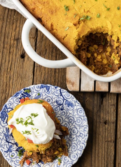 This satisfying, comforting Pulled Pork Casserole lets you get a dinner the whole family will love on the table even on busy weeknights. Saucy, succulent pulled pork with tender black beans and sweet corn is baked under golden brown cornbread in this easy casserole. Serve it alone or topped with all sorts of taco goodies like sour cream, grated cheese, onions, tomatoes, avocado, and taco sauce.