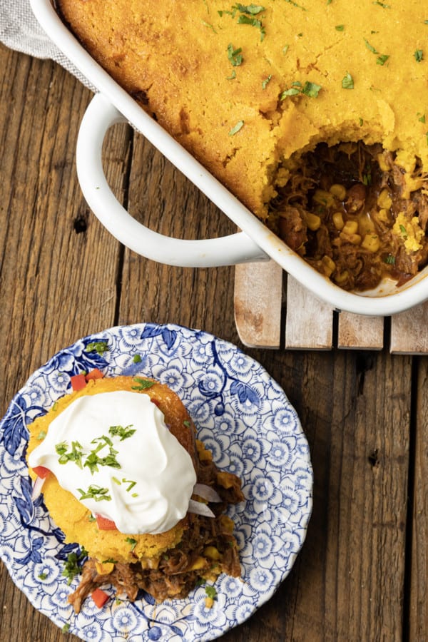 This satisfying, comforting Pulled Pork Casserole lets you get a dinner the whole family will love on the table even on busy weeknights. Saucy, succulent pulled pork with tender black beans and sweet corn is baked under golden brown cornbread in this easy casserole. Serve it alone or topped with all sorts of taco goodies like sour cream, grated cheese, onions, tomatoes, avocado, and taco sauce.