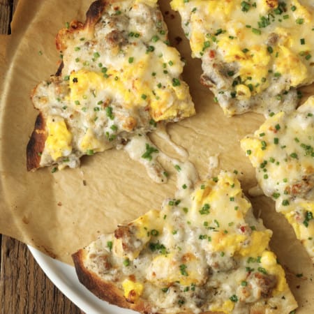 Hold onto your socks, because Sausage Gravy Breakfast Pizza just might knock them off! This ultimate comfort food mashup is coming soon to a breakfast, brunch (or dinner!) table near you. Chewy pizza crust is topped with cheesy, fluffy scrambled eggs, savoury, flavourful, creamy sausage gravy, and fragrant chives in this deliciously different pizza. Made on naan bread (or pre-baked pizza shells, homemade or purchased), these pizzas come together in just moments, too!