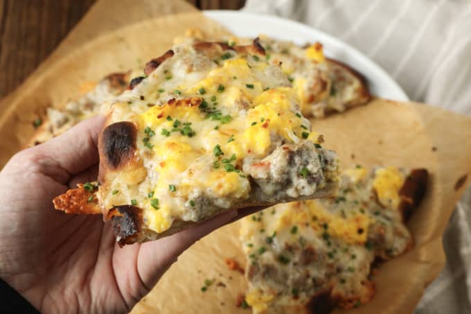 Hold onto your socks, because Sausage Gravy Breakfast Pizza just might knock them off! This ultimate comfort food mashup is coming soon to a breakfast, brunch (or dinner!) table near you. Chewy pizza crust is topped with cheesy, fluffy scrambled eggs, savoury, flavourful, creamy sausage gravy, and fragrant chives in this deliciously different pizza. Made on naan bread (or pre-baked pizza shells, homemade or purchased), these pizzas come together in just moments, too!