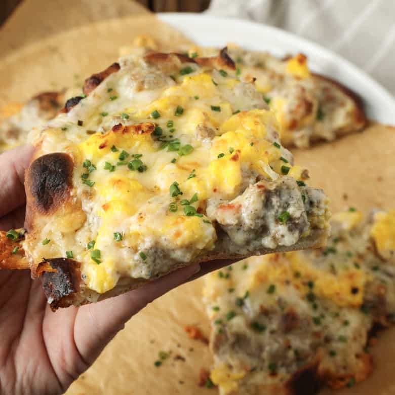 Hold onto your socks, because Sausage Gravy Breakfast Pizza just might knock them off! This ultimate comfort food mashup is coming soon to a breakfast, brunch (or dinner!) table near you. Chewy pizza crust is topped with cheesy, fluffy scrambled eggs, savoury, flavourful, creamy sausage gravy, and fragrant chives in this deliciously different pizza. Made on naan bread (or pre-baked pizza shells, homemade or purchased), these pizzas come together in just moments, too!