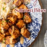 crispy air fryer bang bang salmon bites drizzled with sauce served with ice on a blue and white floral plate with text overlay describing the photo