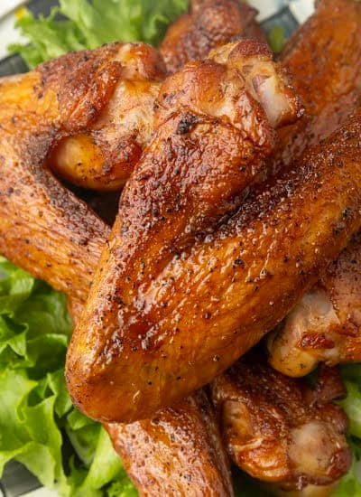 smoked turkey wings on top of a black and white checked plate with lettuce