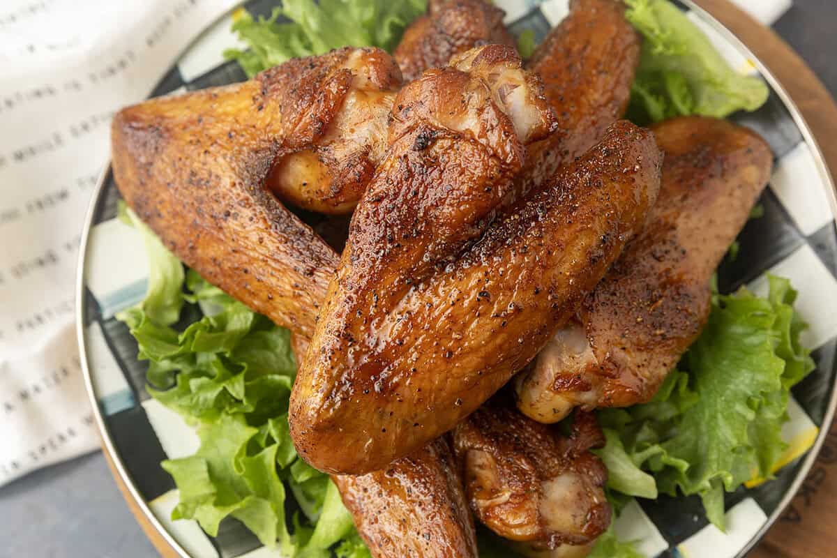 smoked turkey wings on top of a black and white checked plate with lettuce