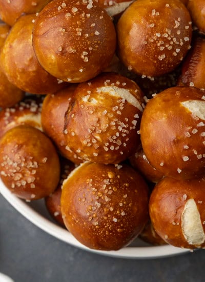 sourdough discard soft pretzel bites in a bowl with mustard and queso