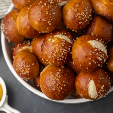 sourdough discard soft pretzel bites in a bowl with mustard and queso