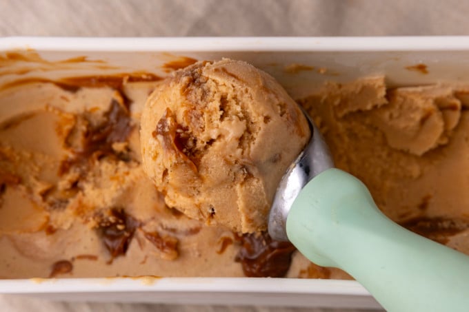 A scoop of dulce de leche ice cream with caramel sauce on top.