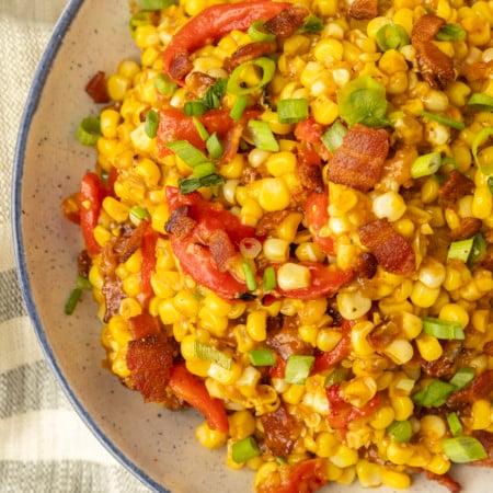fried sweet corn with bacon, green onions and roasted red peppers in a bowl
