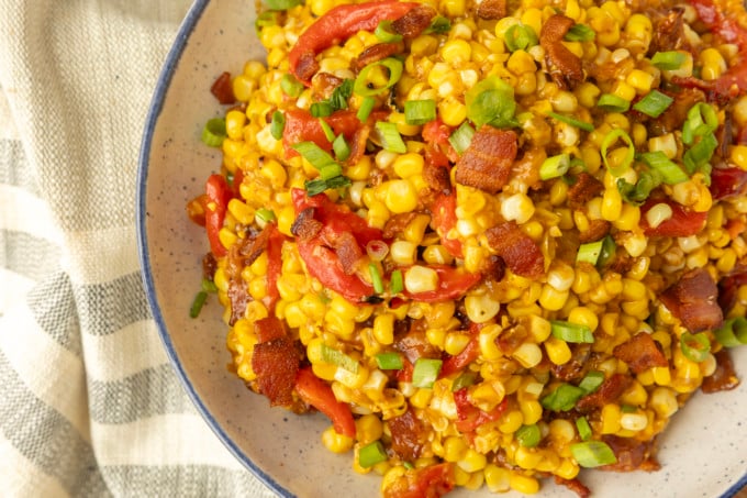 fried sweet corn with bacon, green onions and roasted red peppers in a bowl