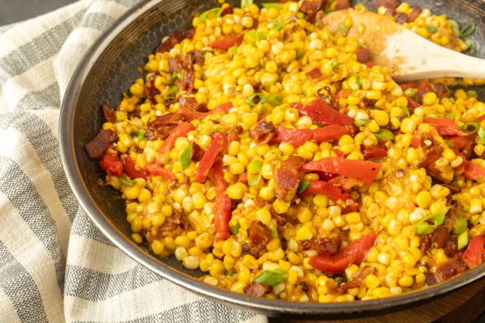 fried sweet corn with bacon, green onions and roasted red peppers in a bowl
