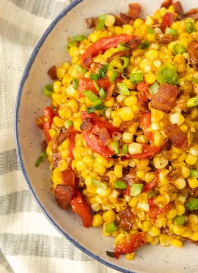 fried sweet corn with bacon, green onions and roasted red peppers in a bowl
