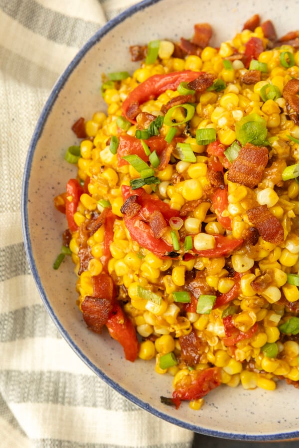 fried sweet corn with bacon, green onions and roasted red peppers in a bowl