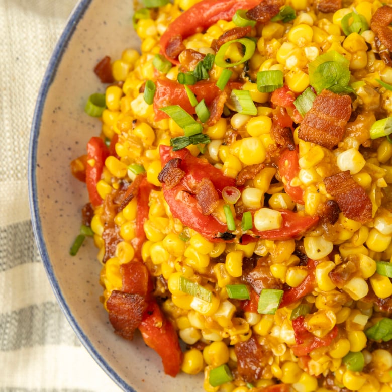 fried sweet corn with bacon, green onions and roasted red peppers in a bowl