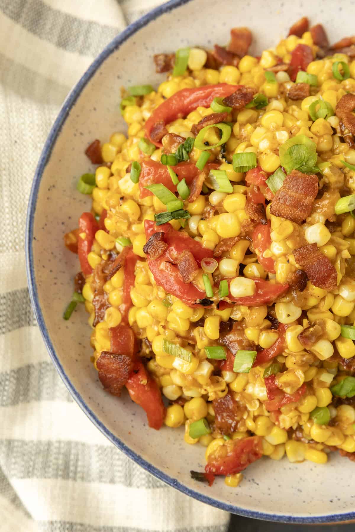 fried sweet corn with bacon, green onions and roasted red peppers in a bowl