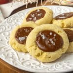dulce de leche thumprint shortbread cookies on a plate with text over the photo describing the contents