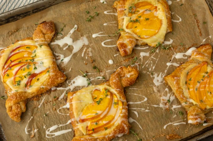 peach cream cheese puff pastry with thyme on parchment lined pan